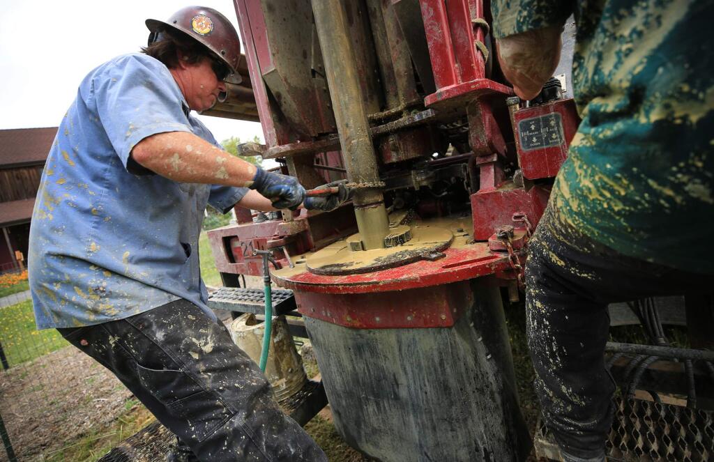Drake Coffe secures another length of pipe to a water well drill bit. (KENT PORTER / The Press Democrat)