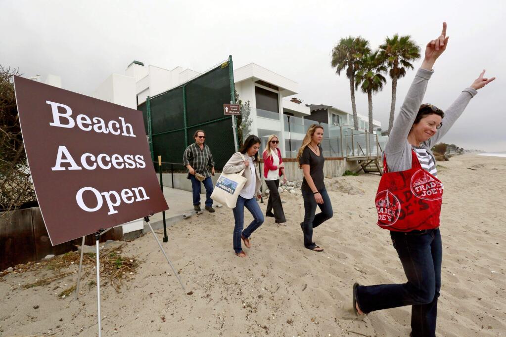 Beachgoers celebrate as they walk onto Carbon Beach, the so-called 'Billionaires' Beach,' by way of an new access route in Malibu. (NICK UT / Associated Press, 2015)