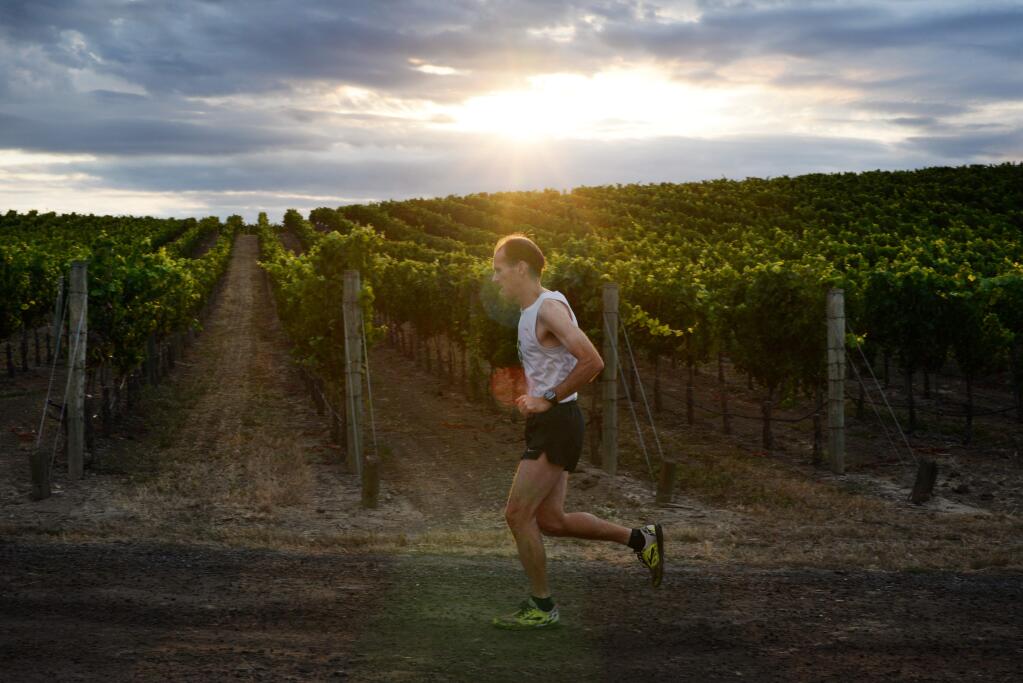John Litzenberg, 45, of Glen Ellen warms up near the vineyards at Cuvaison Estate Wines in Napa before the start of the Napa-to-Sonoma Wine Country Half Marathon on Sunday, July 15, 2015. (ERIK CASTRO/ FOR THE PD)