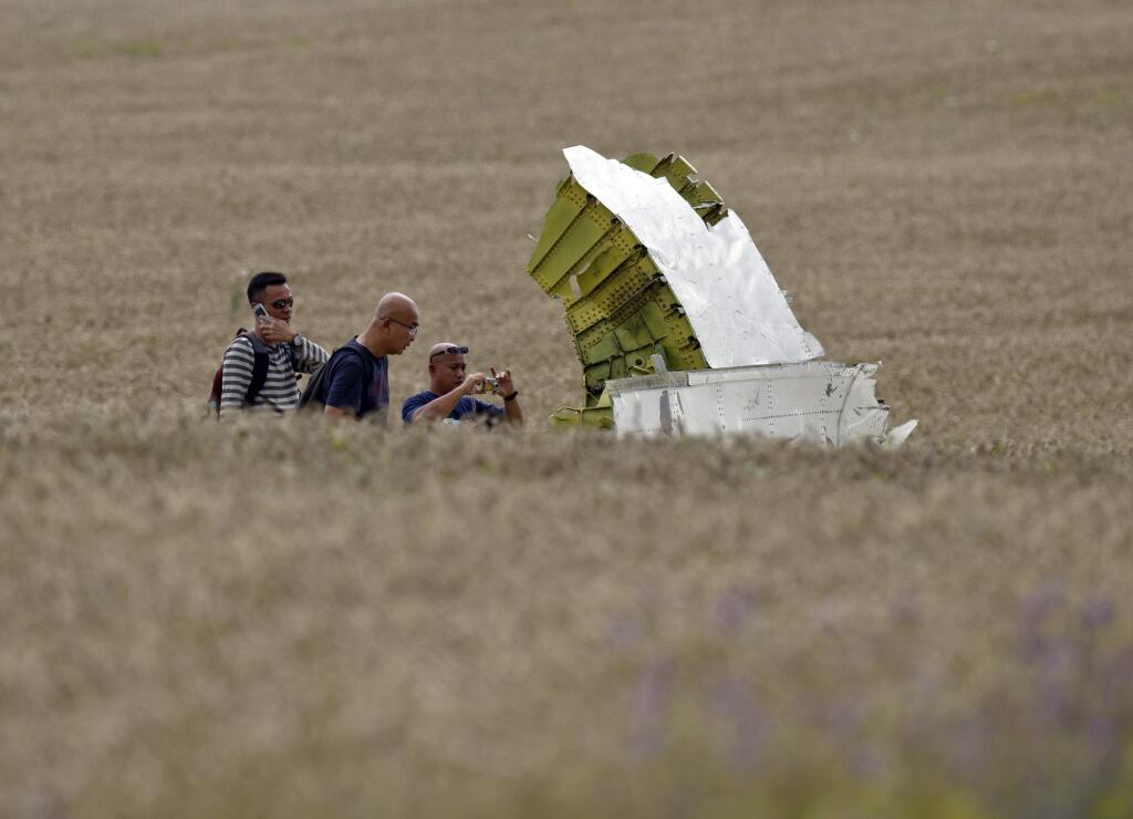 A Malaysian air crash investigator takes pictures in a wheat field at the crash site of Malaysia Airlines Flight 17 near the village of Hrabove, eastern Ukraine, Tuesday, July 22, 2014. (AP Photo/Vadim Ghirda)