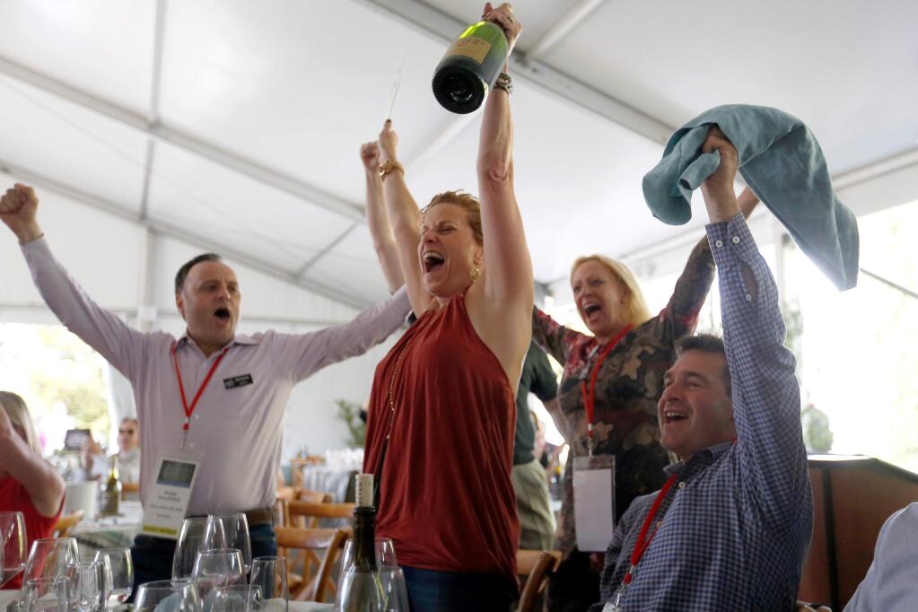 Wendy Heilmann, center, of Pebble Beach Resorts cheers victoriously after winning the final auction lot of 20 cases of Williams Selyem Winery 2015 35th Anniversary Blend Pinot Noir with a bid of $41,000.00 during the Sonoma County Barrel Auction at Vintner's Inn in Santa Rosa, California on Friday, April 29, 2016. (Alvin Jornada / The Press Democrat)