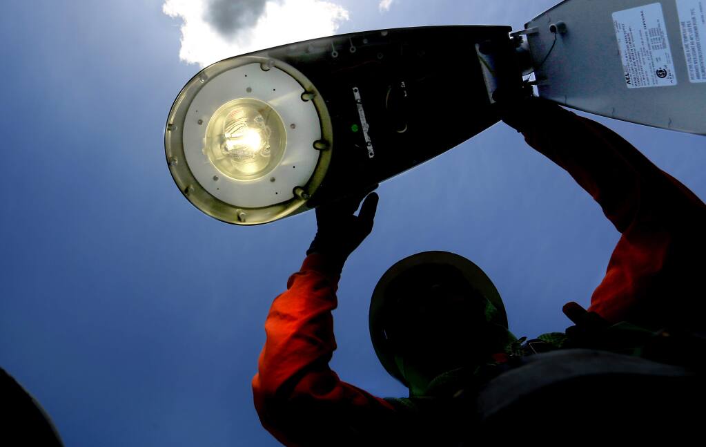 Nathan Moore, and electrician with the City of Santa Rosa, tests a new LED streetlamp in Santa Rosa, Monday May 11, 2015 after taking the old sodium vapor lamp down and updating the pole with the LED fixture.. (Kent Porter / Press Democrat) 2015
