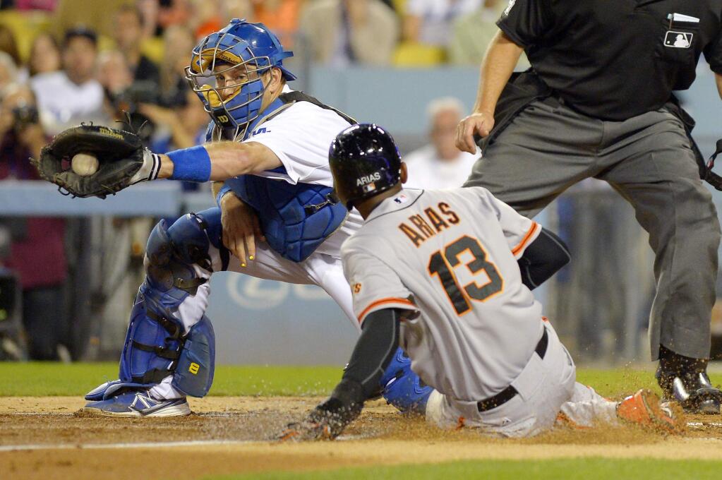 San Francisco Giants' Joaquin Arias, right, is safe at home on a fielders choice by Hunter Pence as Los Angeles Dodgers catcher A.J. Ellis takes a late throw during the third inning of a baseball game, Wednesday, Sept. 24, 2014, in Los Angeles. (AP Photo/Mark J. Terrill)