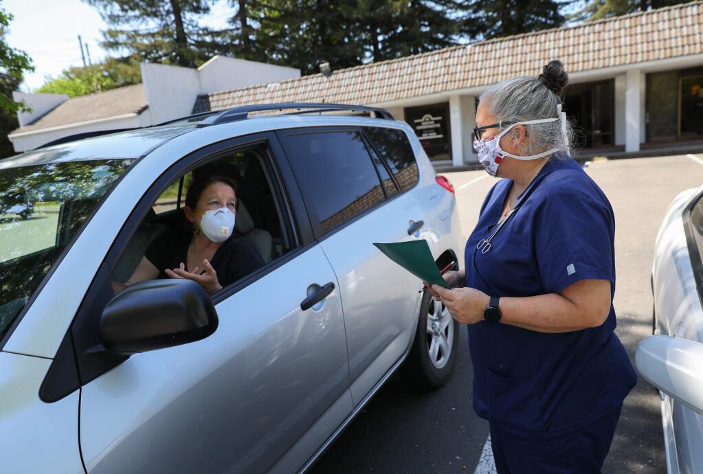 Registered veterinary technician Laurie Bagley, right, takes information from Barbara Gray, president of No Boundaries Animal Rescue, about a cat that she is bringing to be seen by a veterinarian at Wikiup Veterinary Hospital on Friday, May 1, 2020. (Christopher Chung/ The Press Democrat)