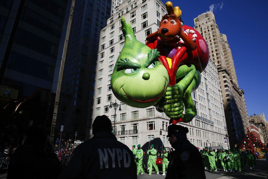 FILE - In this Nov. 22, 2018 file photo, the Grinch balloon floats over Central Park West during the 92nd annual Macy's Thanksgiving Day Parade in New York. Macy's Thanksgiving Day Parade on Thursday, Nov. 28, 2019, will take place amid strong winds that could potentially ground the giant character balloons. The balloons have caused mishaps and injuries in the past when gusts blew them off course. (AP Photo/Eduardo Munoz Alvarez, File)