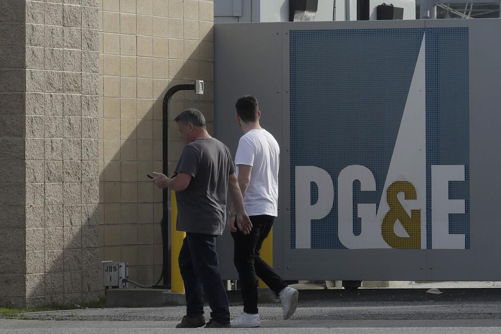 People walk past a Pacific Gas and Electric sign at a PG&E location in San Francisco. (Jeff Chiu / Associated Press, 2020)