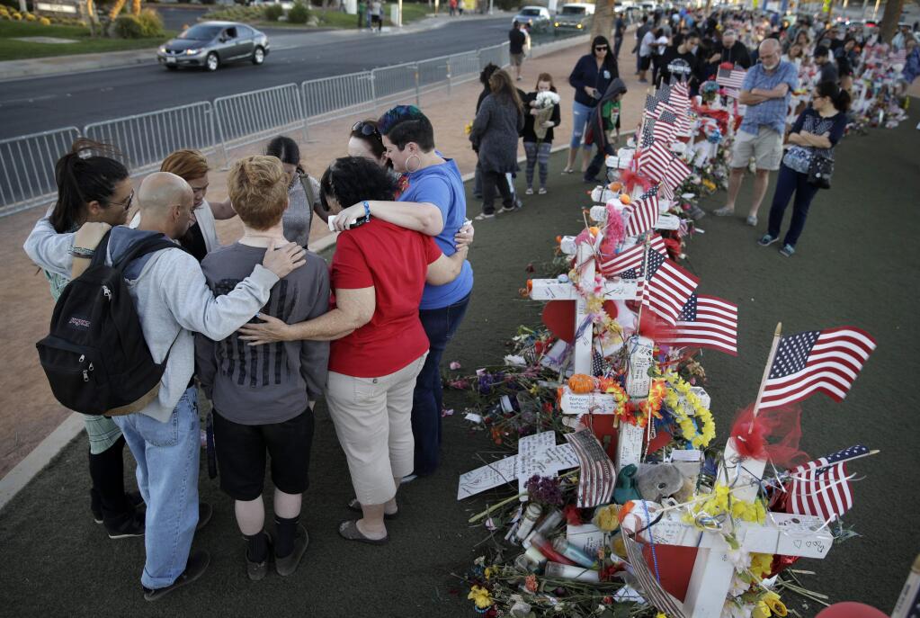 FILE - In this Monday, Oct. 9, 2017 file photo, people pray at a makeshift memorial for victims of a mass shooting in Las Vegas. Gunman Stephen Paddock opened fire Sunday, Oct. 1 from a room at the Mandalay Bay resort and casino, on an outdoor country music concert killing dozens and injuring hundreds. A revised chronology given by investigators for the Las Vegas massacre is intensifying pressure for police to explain how quickly they responded to what would become the deadliest mass shooting in modern U.S. history. (AP Photo/John Locher, File)