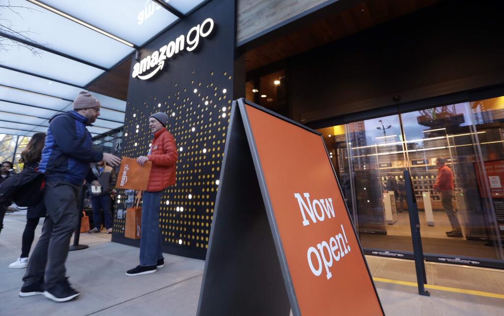A customer is handed a complimentary shopping bag as he heads into an Amazon Go store, Monday, Jan. 22, 2018, in Seattle. More than a year after it introduced the concept, Amazon opened its artificial intelligence-powered Amazon Go store in downtown Seattle on Monday. The store on the bottom floor of the company's Seattle headquarters allows shoppers to scan their smartphone with the Amazon Go app at a turnstile, pick out the items they want and leave. (AP Photo/Elaine Thompson)
