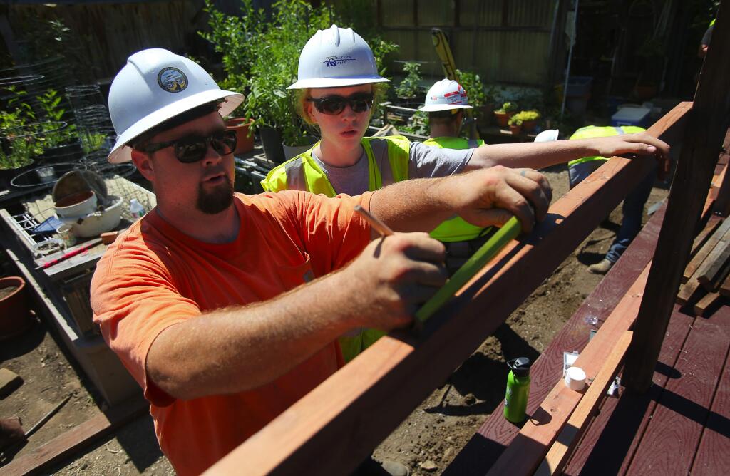North Bay Construction Corps 'Pathway to Paycheck' Boot Camp participant Marcus Coster, right, watches volunteer mentor and trainer Jesse Bjork, a carpenter for Nordby Construction, measure for the placement of posts along a patio at a Habitat for Humanity 'Elder Care Project' home in Santa Rosa on Wednesday, June 21, 2017. (Christopher Chung / The Press Democrat)