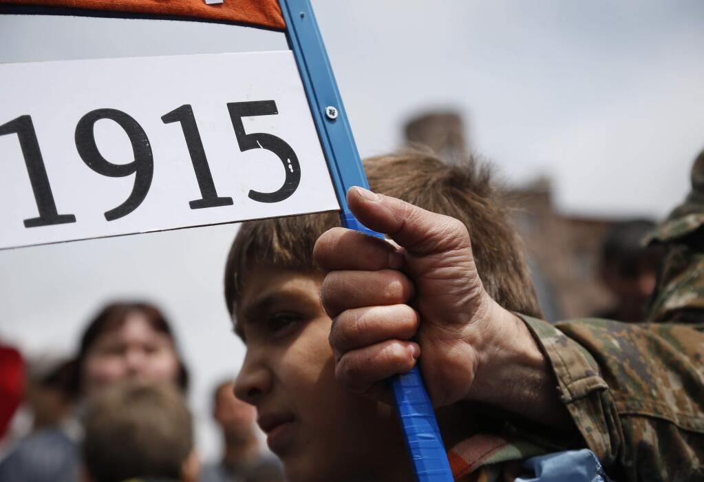An Armenian holds a placard with a sign reading '1915', the year of mass killings of Armenians by Ottoman Turks on a city street in Yerevan, Armenia, Friday, April 24, 2015. Armenians on Friday marked the centenary of what historians estimate to be the slaughter of up to 1.5 million Armenians by Ottoman Turks, an event widely viewed by scholars as genocide. Turkey, however, denies the deaths constituted genocide and says the death toll has been inflated. (AP Photo/Sergei Grits)
