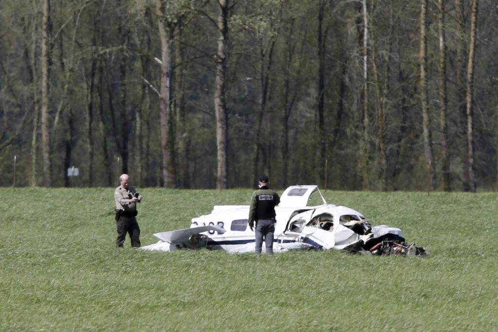 A Linn County Sheriff deputy approaches the scene of a small plane crash north of Harrisburg, Ore., that left four people dead, Friday April 7, 2017. (Collin Andrew/The Register-Guard via AP)