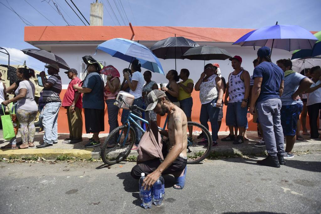 People affected by the passage of Hurricane Maria wait in line at Barrio Obrero to receive supplies from the national Guard, in San Juan, Puerto Rico, Sunday, Sept. 24, 2017. Puerto Rico's nonvoting representative in the U.S. Congress said Sunday that Hurricane Maria's destruction has set the island back decades, even as authorities worked to assess the extent of the damage.(AP Photo/Carlos Giusti)