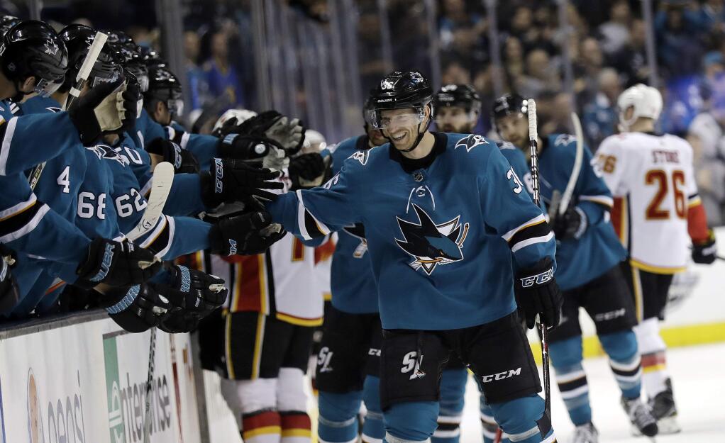 San Jose Sharks' Jannik Hansen, right, celebrates with teammates after scoring against the Calgary Flames during the first period of an NHL hockey game Saturday, March 24, 2018, in San Jose, Calif. (AP Photo/Marcio Jose Sanchez)