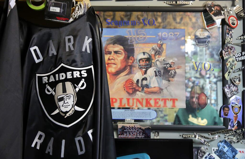 The cape that Mike Umphenour wore as part of his Dark Raider costume hangs in his garage next to a mirror featuring Jim Plunkett, in Windsor, on Sunday, December 13, 2015. (Christopher Chung/ The Press Democrat)