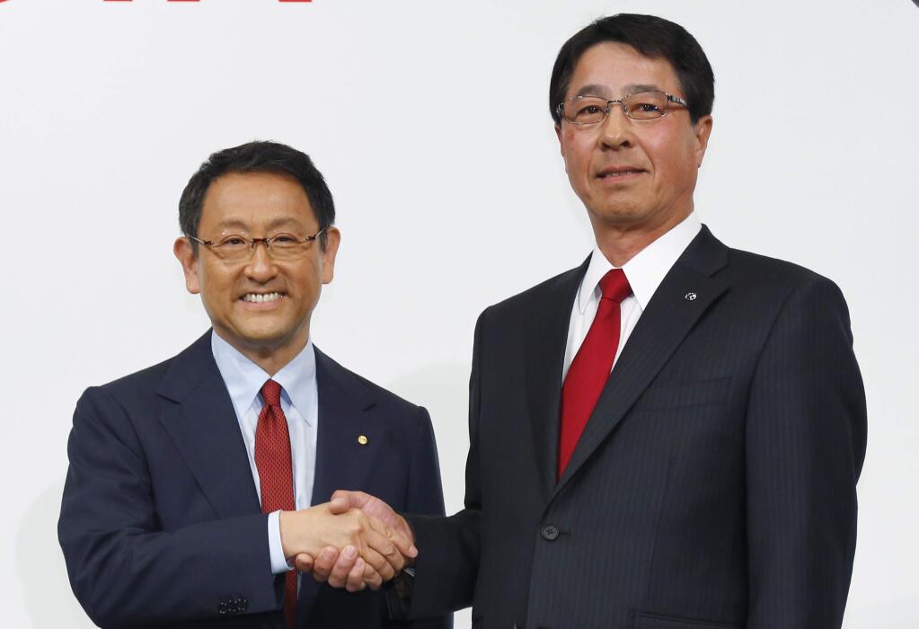 Toyota Motor Corp. President Akio Toyoda, left, and Mazda Motor Corp. President Masamichi Kogai pose for photographers prior to a press conference in Tokyo Wednesday, May 13, 2015. Toyota and Japanese rival Mazda are expanding their partnership to a long-term one focusing on technologies in the areas of safety and fuel efficiency. Toyoda expressed interest in Hiroshima-based Mazda's fuel-efficient technology for gasoline engines and diesel vehicles called Skyactive. (AP Photo/Shizuo Kambayashi)