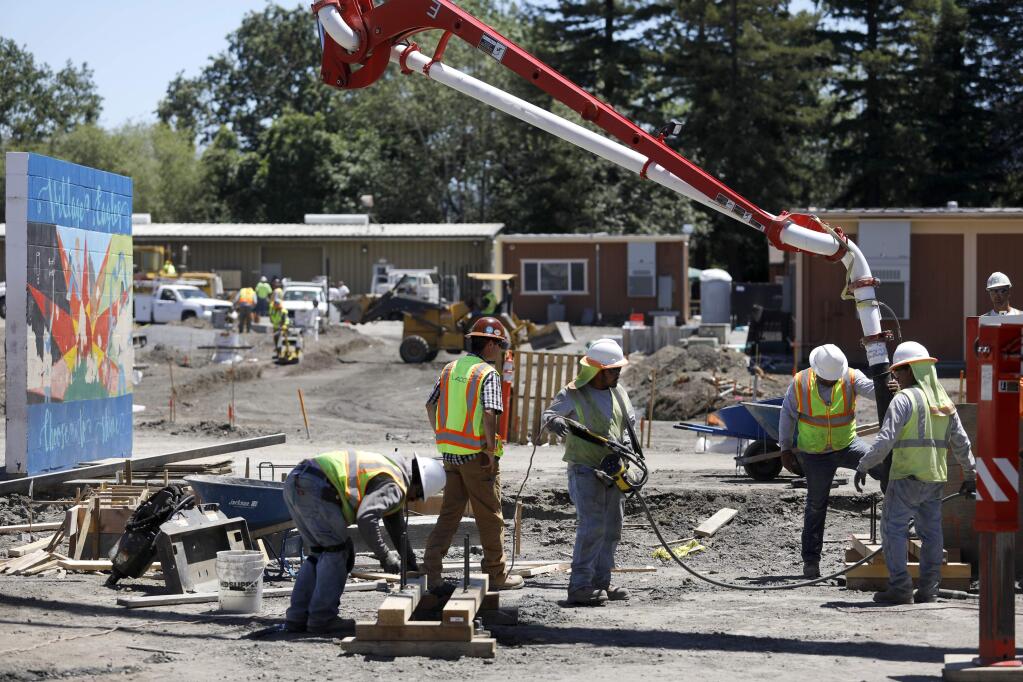 Workers from USA SHADE work to pour concrete footings for a large shade structure over the area for a new playground at Village Elementary School on Monday, July 9, 2018 in Santa Rosa, California. The school is undergoing $11.4 million in upgrades. (BETH SCHLANKER/The Press Democrat)