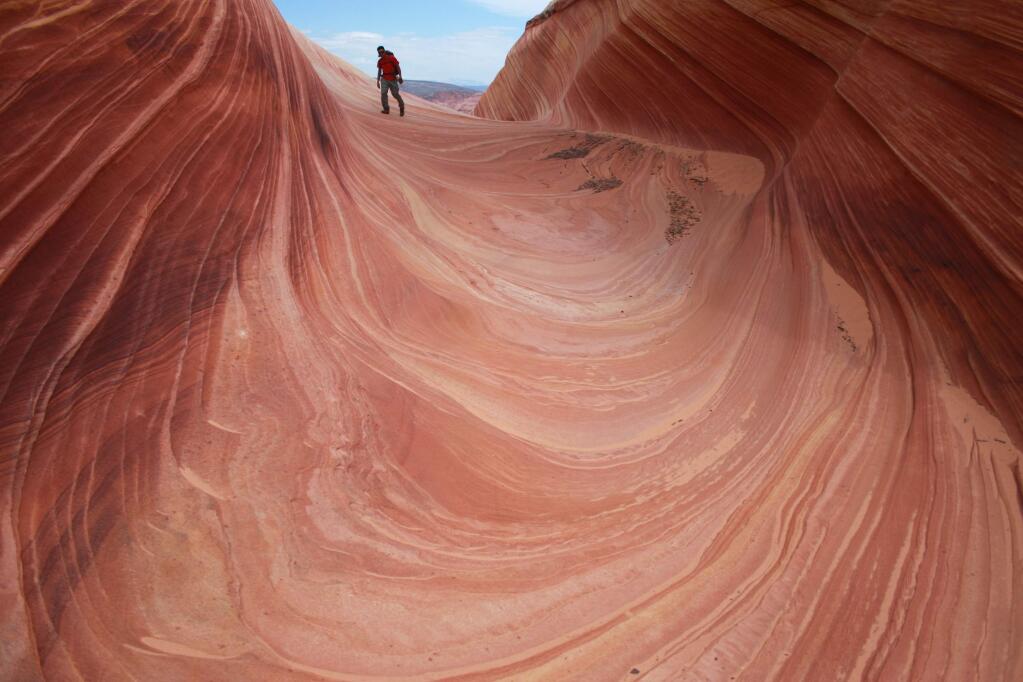 A hiker walks on a rock formation known as the Wave in the Vermilion Cliffs National Monument in Arizona. (BRIAN WITTE / Associated Press, 2013)