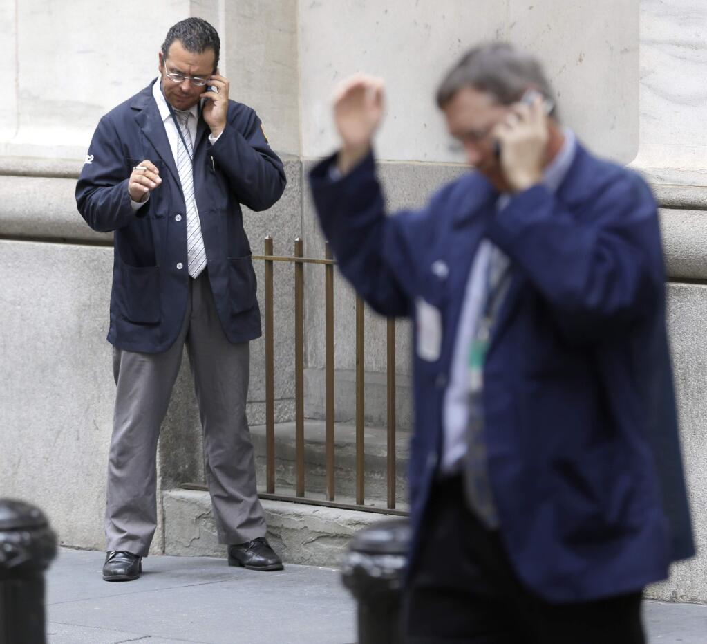Traders smoke and talk on their phones in front of the New York Stock Exchange, Monday, Aug. 24, 2015. U.S. stock markets plunged in early trading Monday following a big drop in Chinese stocks. (AP Photo/Seth Wenig)