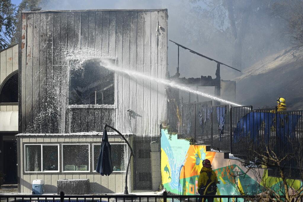 Firefighters shoot water at the Lafayette Tennis Club building in Lafayette, Calif., on Sunday, Oct. 27, 2019. Crews battled a 6-acre grass fire between Camino Diablo and Springbrook Road near State Route 24. (Jose Carlos Fajardo/Bay Area News Group/San Jose Mercury News via AP)