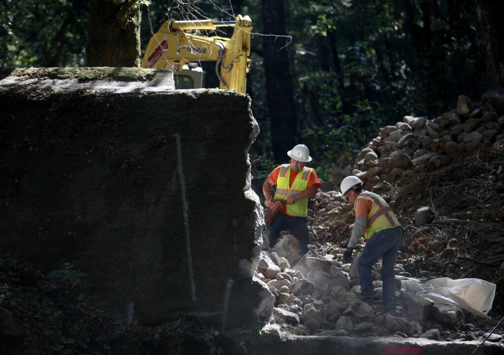 Rafael Cervantes, left, and Fernando Callivillo, employees with Hanford A.R.C., work to demolish the Glenn Oaks flashboard dam as part of the construction of a fish way for steelhead trout on Stuart Creek on Friday, September 12, 2014 in Sonoma, California. (BETH SCHLANKER/ The Press Democrat)