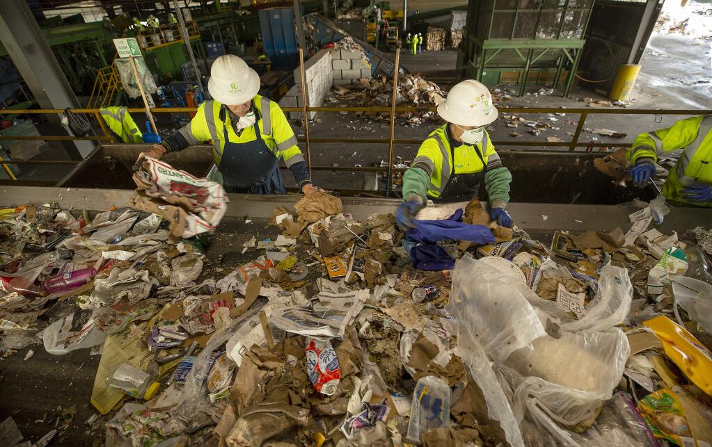 Workers separate cardboard from single stream home recycling cans. (photo by John Burgess/The Press Democrat)