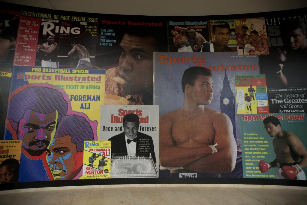 FILE - In this June 4, 2016, file photo large posters of mostly Sports Illustrated magazine covers are displayed at the 'I Am The Greatest, Muhammad Ali' exhibition at the O2 arena, which hosts high profile boxing fights in London. Sports Illustrated is being sold for $110 million, but the seller will continue running the iconic magazine under a licensing deal. Authentic Brands Group is buying Sports Illustrated from Meredith Corp. (AP Photo/Matt Dunham, File)
