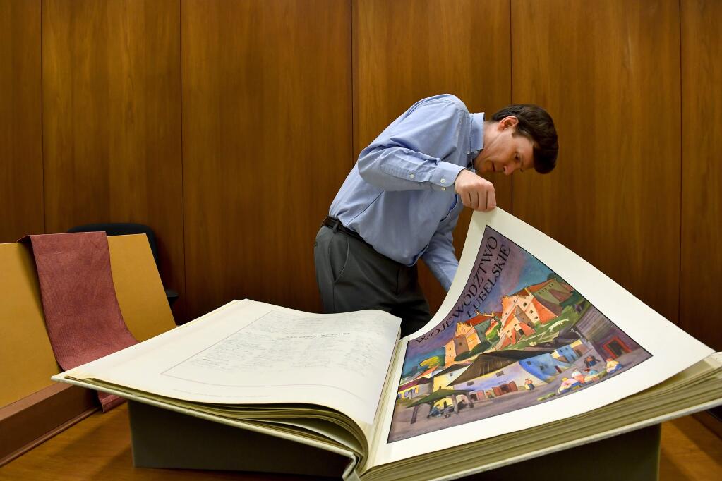 Sahr Conway-Lanz looks through one of the 111 volumes of books signed by 5 million Polish citizens. MUST CREDIT: Washington Post photo by Katherine Frey