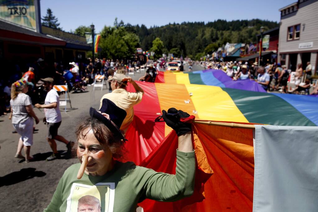 Jackie Mendoza carries a pride flag with a group from Food For Thought during the Sonoma County Gay Pride Parade in Guerneville, on Sunday, June 5, 2016. (BETH SCHLANKER/ The Press Democrat)