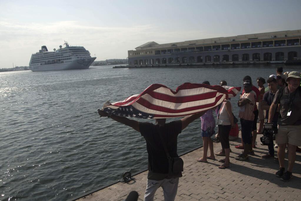 Daniel Miranda waves a U.S. flag as he watches the arrival of Carnival's Adonia cruise ship from Miami, in Havana, Cuba, Monday, May 2, 2016. The Adonia's arrival is the first step toward a future in which thousands of ships a year could cross the Florida Straits, long closed to most U.S.-Cuba traffic due to tensions that once brought the world to the brink of nuclear war. (AP Photo/Fernando Medina)