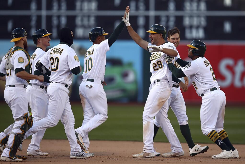 The Oakland Athletics' Matt Olson (28) is congratulated by teammates, including Marcus Semien (10) ,after driving in the winning run against the Chicago White Sox in the 14th inning Wednesday, April 18, 2018, in Oakland. (AP Photo/Ben Margot)