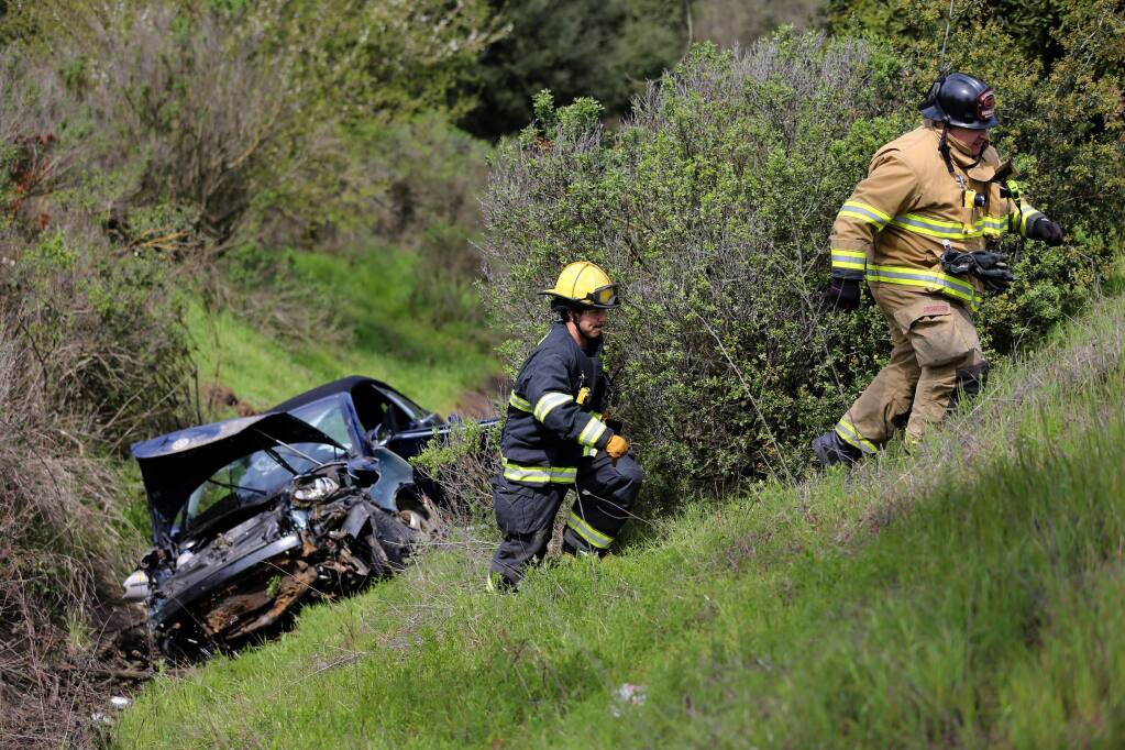 Rancho Adobe firefighters work at the scene of a crash after a car went down an embankment off southbound Highway 101 in Cotati, California, on Sunday, March 24, 2019. (RAMIN RAHIMIAN/ FOR PD)