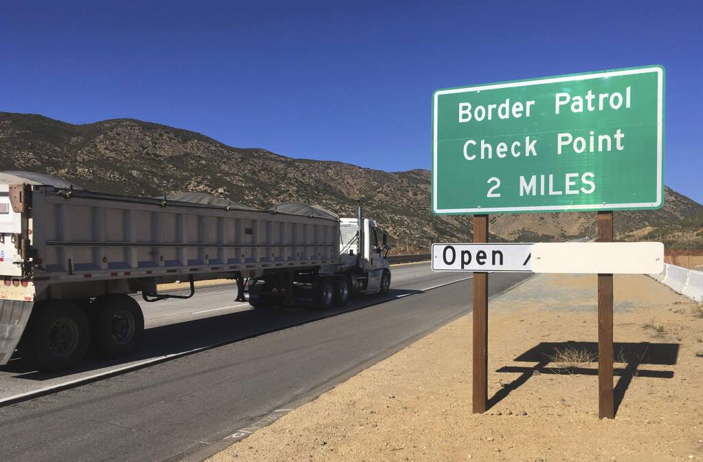In this Thursday, Dec. 14, 2017 photo, a sign warns of the upcoming California Pine Valley checkpoint, on the main route from Arizona to San Diego. California legalizes marijuana for recreational use Jan. 1 but that won't stop federal agents from seizing small amounts on busy freeways and backcountry highways. Possession will still be prohibited at eight Border Patrol checkpoints in California, a daily demonstration of state and federal law colliding. (AP Photo/Elliot Spagat)