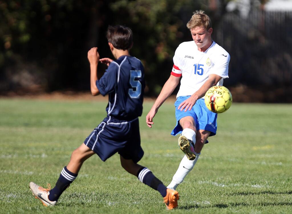 Rincon Valley Christian's James Leng, right, boots the ball away as The Bay School's James Fowler pressures him during the game held at Rincon Valley Christian, Monday, September 15, 2014.(Crista Jeremiason / The Press Democrat)