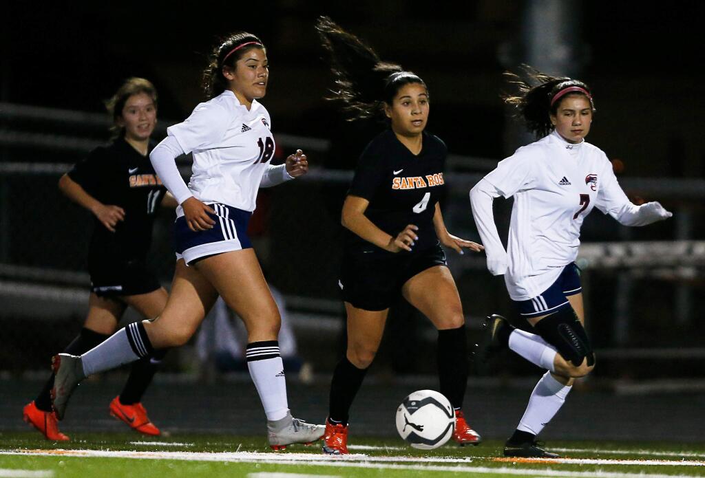 Santa Rosa's Chelsea Juarez-Flores (4), center, looks to cross the ball while pursued by Rancho Cotate's Daniela Henriquez (18), left, and Delia Rantissi (7) during the first half of a girls varsity soccer match between Rancho Cotate and Santa Rosa high schools in Santa Rosa, California, on Thursday, February 13, 2020. (Alvin Jornada / The Press Democrat)