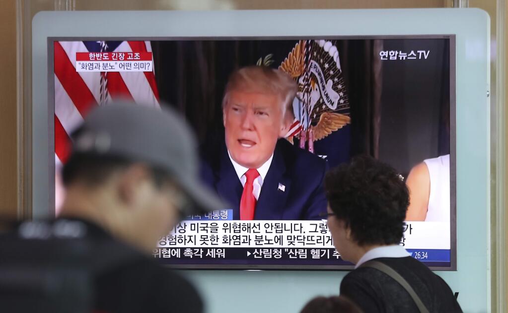 People walk by a TV screen showing a local news program reporting with an image of U.S. President Donald Trump at the Seoul Train Station in Seoul, South Korea, Wednesday, Aug. 9, 2017. North Korea and the United States traded escalating threats, with President Donald Trump threatening Pyongyang 'with fire and fury like the world has never seen' and the North's military claiming Wednesday it was examining its plans for attacking Guam. (AP Photo/Lee Jin-man)