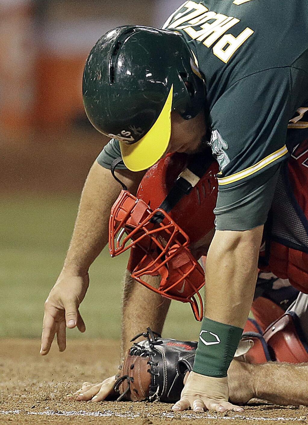 Oakland Athletics' Josh Phegley, top, scores as he falls on Los Angeles Angels catcher Chris Iannetta in the third inning of a baseball game Monday, Aug. 31, 2015, in Oakland, Calif. Phegley scored on a double by Jake Smolinski. (AP Photo/Ben Margot)