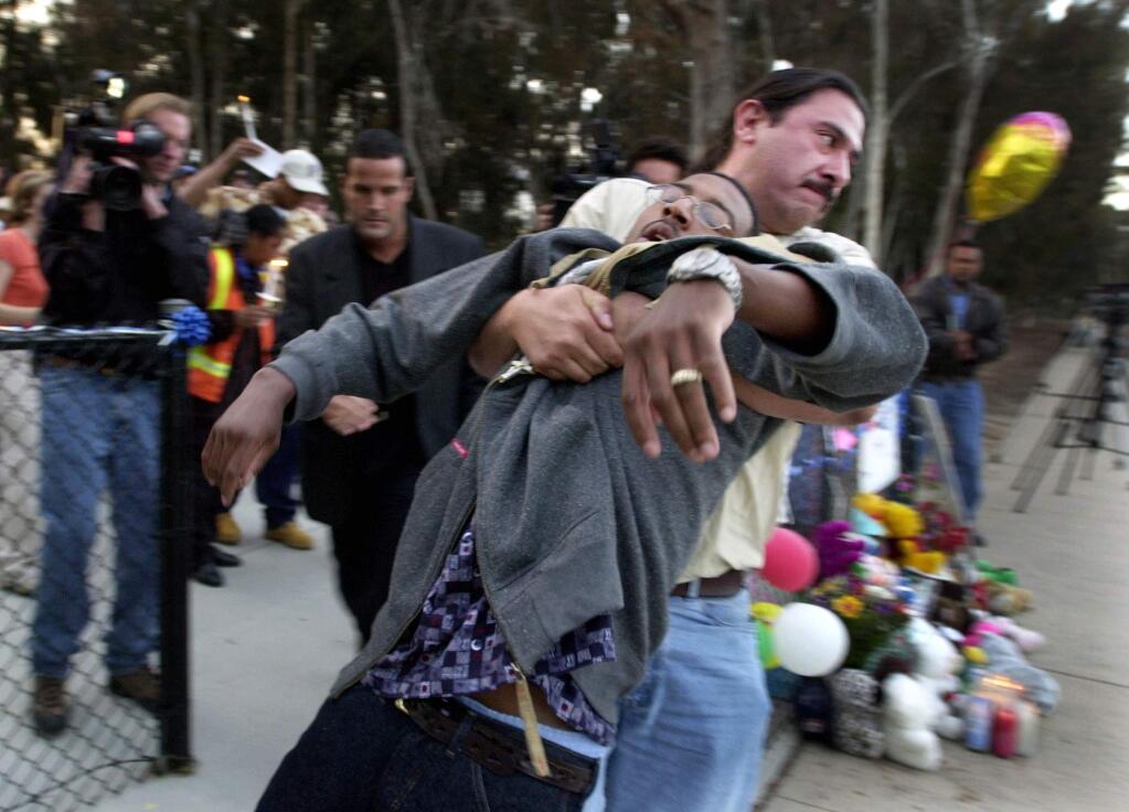 In a May 4, 2002 photo, Tieray Jones is assisted by Bill Garcia, coordinator of the volunteer search efforts, after Jones collapsed during a candlelight vigil for Jahi Turner in Golden Hill, Calif. Jones was arrested Monday, April 18, 2016, by U.S. Marshals and Raleigh Police Department officers in Rocky Mount, North Carolina, east of Raleigh. California officials plan to request the 37-year-old man be extradited to the state to face charges of murder and felony child abuse causing death, in the disappearance of Jahi Turner on April 25, 2002, San Diego County District Attorney Bonnie Dumanis said. (Peggy Peattie/San Diego Union-Tribune via AP)