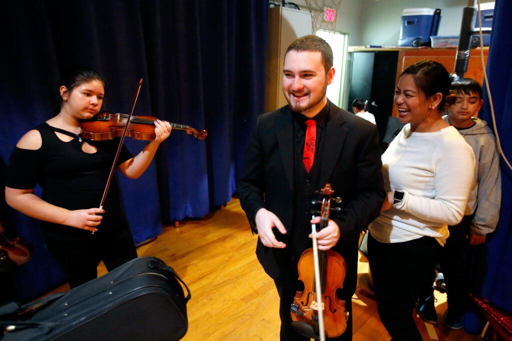 Violin teacher Victor Vasquez, center, chats with chorus teacher Dawn Moore, second from right, before Vasquez's fifth and sixth grade violin class performs at Bellevue Elementary School's Winter Wonderland festival, in Santa Rosa, California, on Tuesday, December 18, 2018. (Alvin Jornada / The Press Democrat)