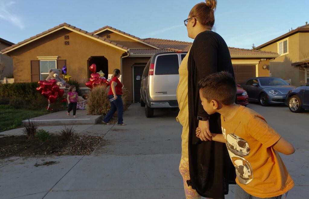 Neighbor Avery Sanchez, 6, peeks behinds his mother, Liza Tozier after dropping off his large 'Teddy' for the children who lived on a home where police arrested a couple on Sunday accused of holding 13 children captive in Perris, Calif., Thursday, Jan. 18, 2018. The parents of 13 children and young adults have pleaded not guilty in a California court to numerous charges that they tortured and abused the siblings for years. David and Louise Turpin were each ordered held on $12 million bail after entering their pleas Thursday and were scheduled to return to court on Feb. 23. (AP Photo/Damian Dovarganes)