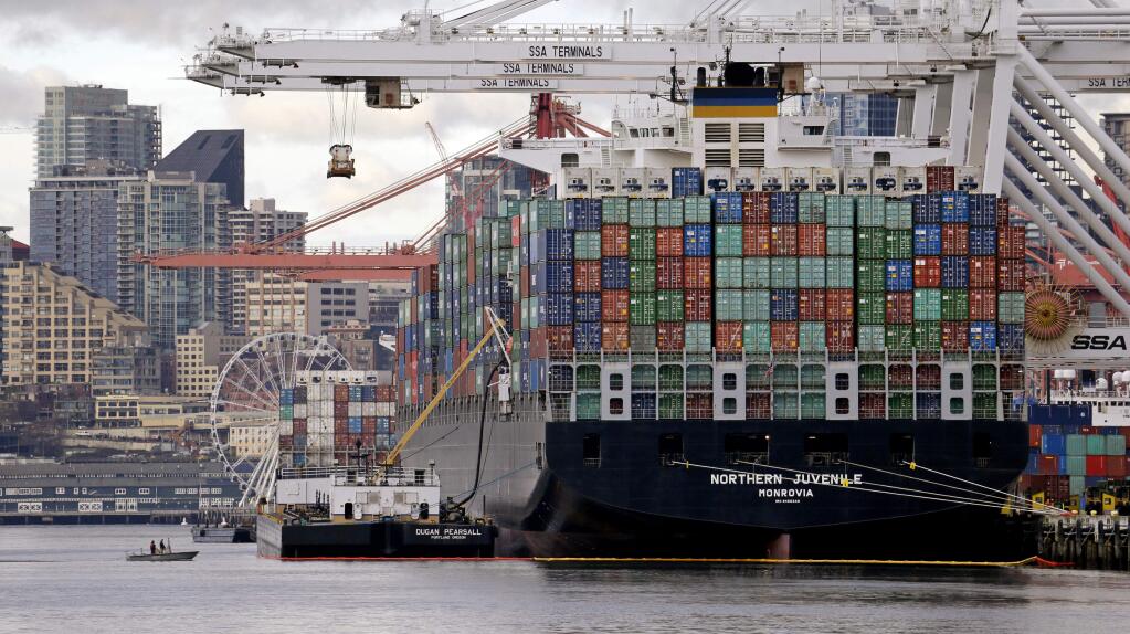 A tiny boat pulls up to a container ship being loaded at the Port of Seattle, Monday, Feb. 9, 2015, in Seattle. (AP Photo/Elaine Thompson)