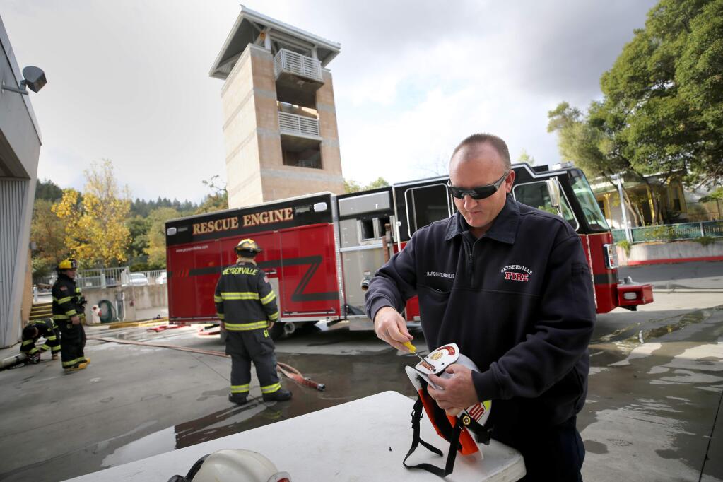 Geyserville Fire Protection District Chief Marshall Turbeville attaches a fire chief badge that belonged to his late father to his new helmet at the fire station in Geyserville on Wednesday, November 27, 2019. (BETH SCHLANKER/ The Press Democrat)