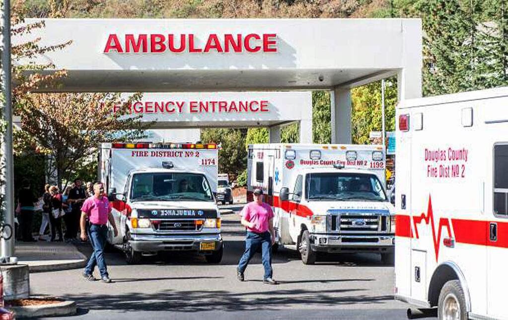 Paramedics return to their ambulances after delivering patients to Mercy Medical Center in Roseburg, Ore., following a deadly shooting at Umpqua Community College, in Roseburg, Thursday, Oct. 1, 2015. (Aaron Yost/Roseburg News-Review via AP)