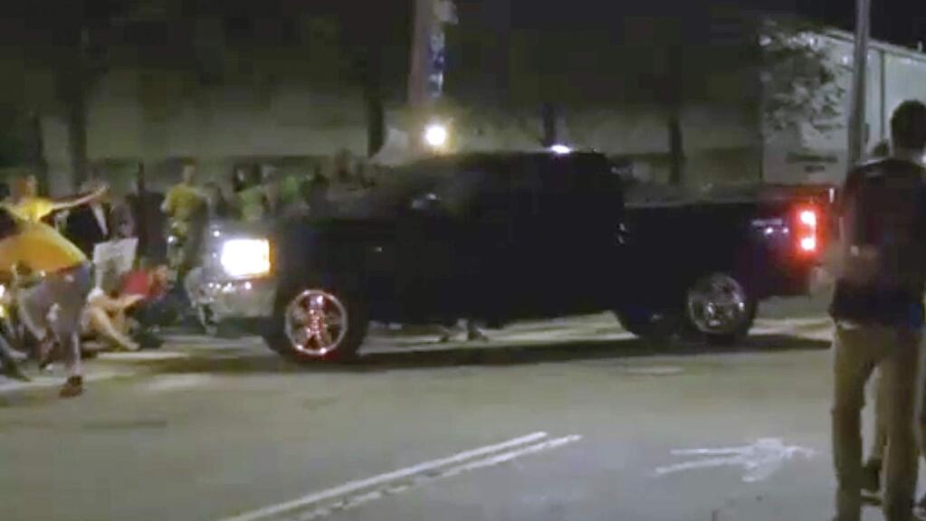 In this still image from video provided by WLNE-TV, protesters blocking an entrance to the Donald W. Wyatt Detention Facility begin to move as a pickup truck approaches, Wednesday night, Aug. 14, 2019, in Central Falls, R.I. The group, which was protesting federal immigration policies, said at least two people were injured. Rhode Island's attorney general said he is investigating the incident. (WLNE-TV via AP)MANDATORY CREDIT