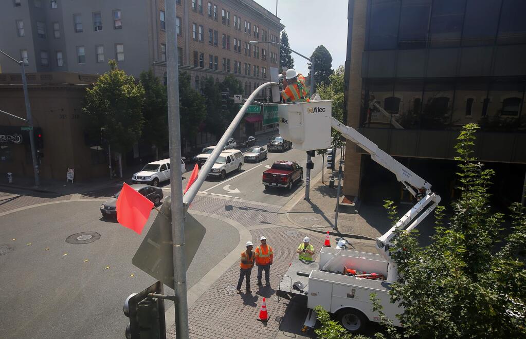 Jack Emerson, of Mike Brown Electric, installs a left turn yield sign at Fifth Street and Mendocino Avenue, in Santa Rosa, on Wednesday, July 27, 2016. (Christopher Chung/ The Press Democrat)