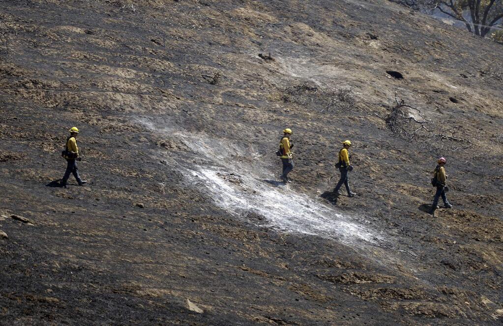 A fire crew from North Lake Tahoe walk across a burned hillside in Solano County north of Winters, Calif., Thursday, July 5, 2018. (Joel Rosenbaum/The Vacaville Reporter via AP)
