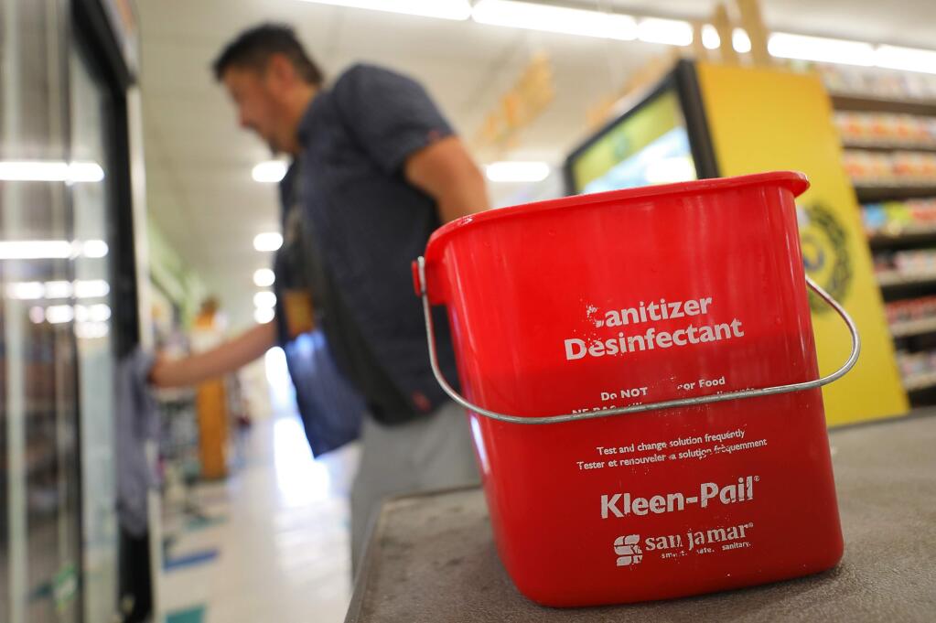 Front end manager Greg Goben, uses a disinfectant to wipe down surfaces that are frequently touched by customers at Community Market, in Santa Rosa on Thursday, March 12, 2020. (Christopher Chung/ The Press Democrat)