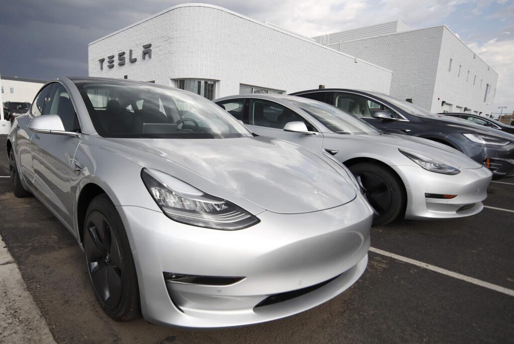 FILE- In this July 8, 2018, file photo, 2018 Model 3 sedans sit on display outside a Tesla showroom in Littleton, Colo. On Thursday, Aug. 9, Tesla shares have dropped back to near the level they were trading at before CEO Elon Musk tweeted Tuesday that he may take the company private. (AP Photo/David Zalubowski, File)