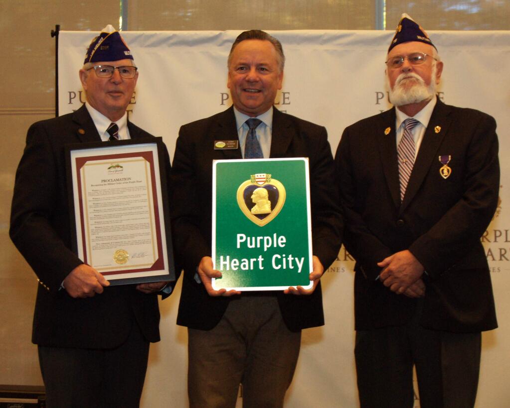 Jim Anderson and John Logan, left and right, of Military Order of the Purple Heart present Yountville Mayor John Dunbar with a Purple Heart City sign and proclamation Nov. 2, 2016, at the Yountville Veterans Home in Napa Valley. (JOHN GAY)
