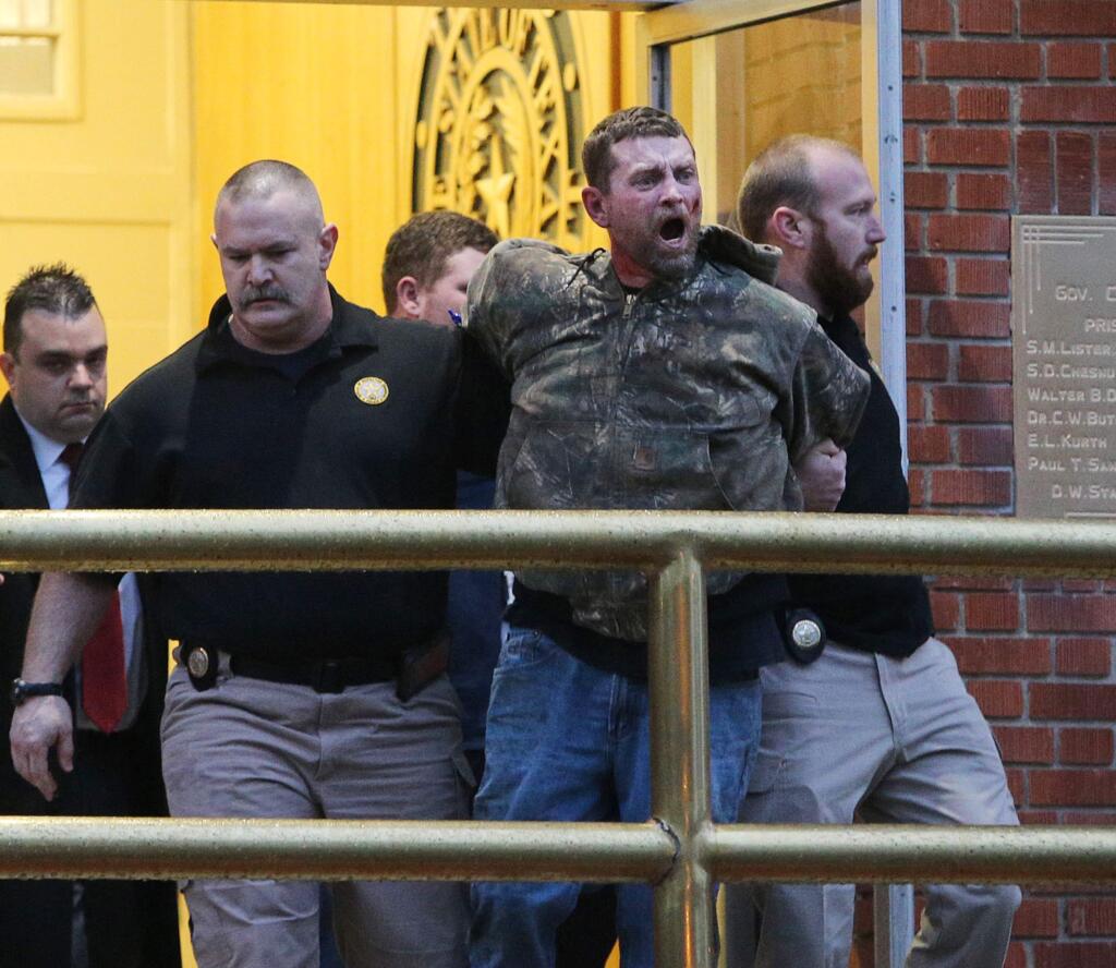 In this Thursday, Feb. 28, 2019 photo, Gordon Coble, center, is led out of the of the Texas State Penitentiary in Huntsville, Texas, after reacting to the execution of his father, Billie Wayne Coble. Chaos erupted outside Texas' death chamber Thursday night when the son of the condemned inmate pounded on the chamber windows, shouted obscenities and threw fists after his father spoke his final words. (Jerry Larson/Waco Tribune-Herald via AP)