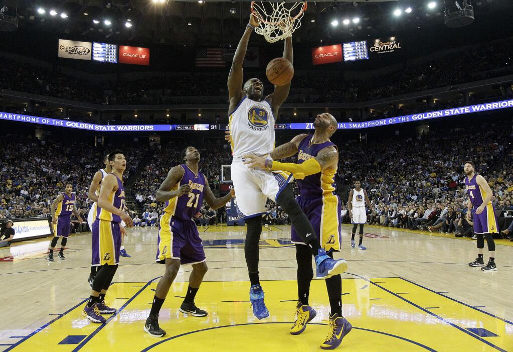 Golden State Warriors center Festus Ezeli (31) dunks over Los Angeles Lakers forward Ed Davis (21) and forward Carlos Boozer, right, during the first half of an NBA basketball game in Oakland, Calif., Monday, March 16, 2015. The Warriors won 108-105. (AP Photo/Jeff Chiu)